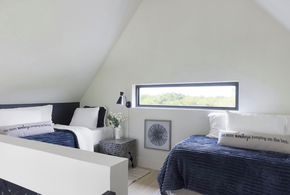 A bedroom with two beds, a window, and a view of greenery.