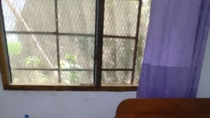 Un dormitorio con cama, una mesita de madera y una ventana con vistas a zonas verdes.