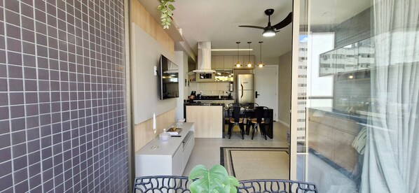 A modern kitchen with a dining area, a ceiling fan, and a view through a glass door.