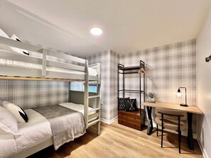 Une petite pièce comprenant un lit superposé, un bureau avec une chaise et une petite plante.