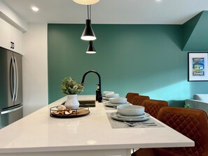 Une cuisine moderne dotée d’un îlot central, d’un évier et d’un coin repas avec des chaises.