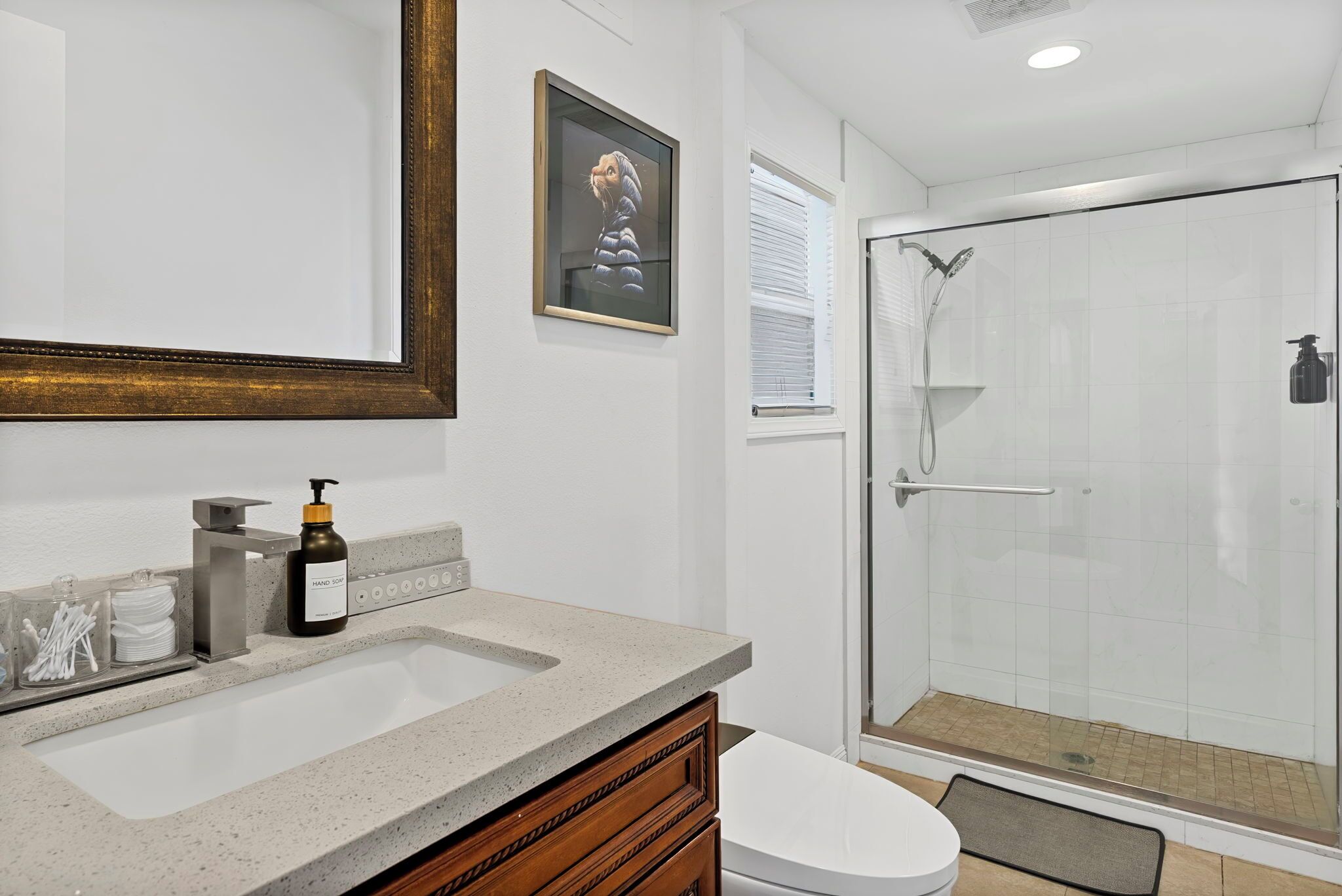 A modern bathroom with a large mirror, a sink, a toilet, and a glass-enclosed shower.