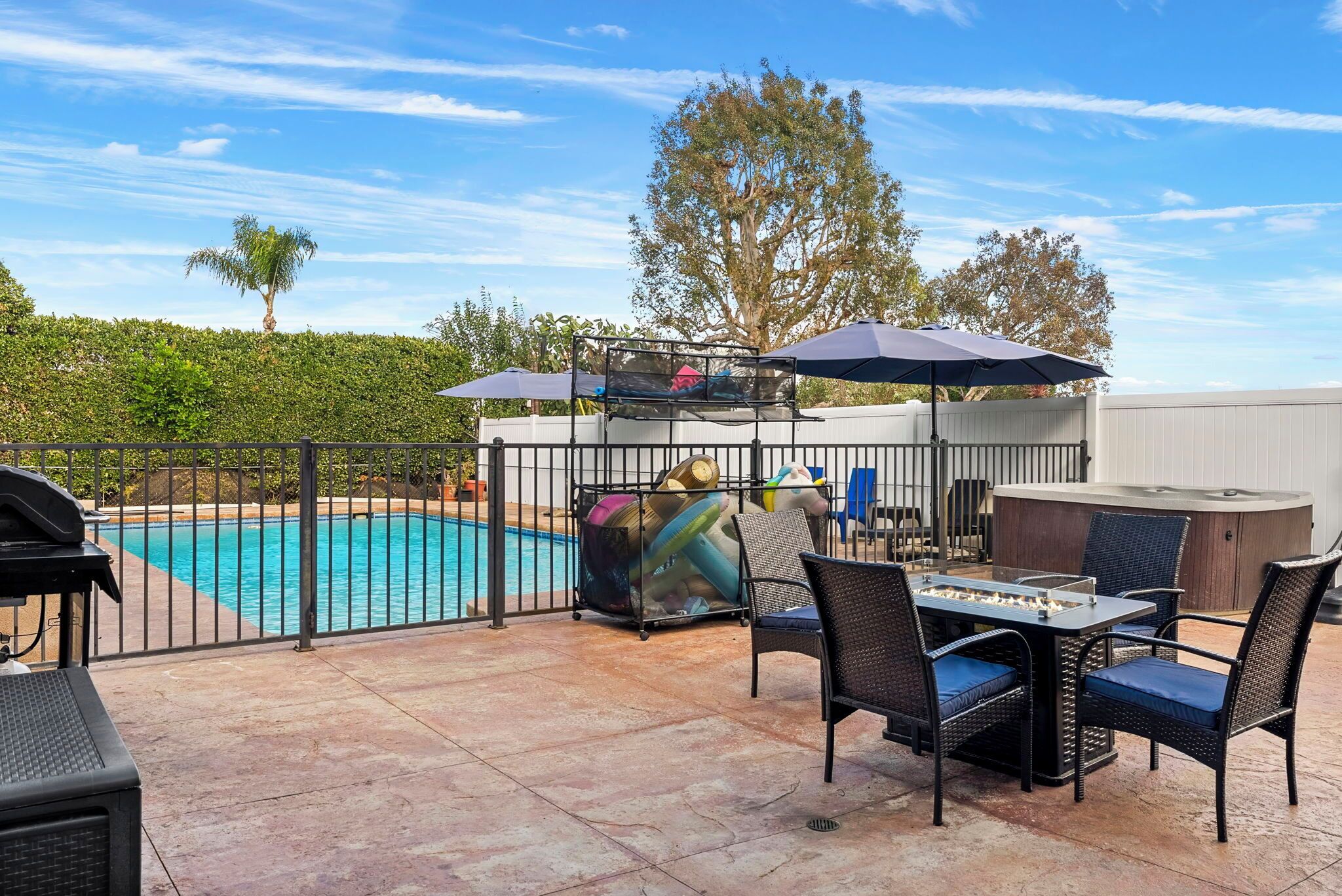 An outdoor patio with a pool, a table with chairs, and a hot tub.
