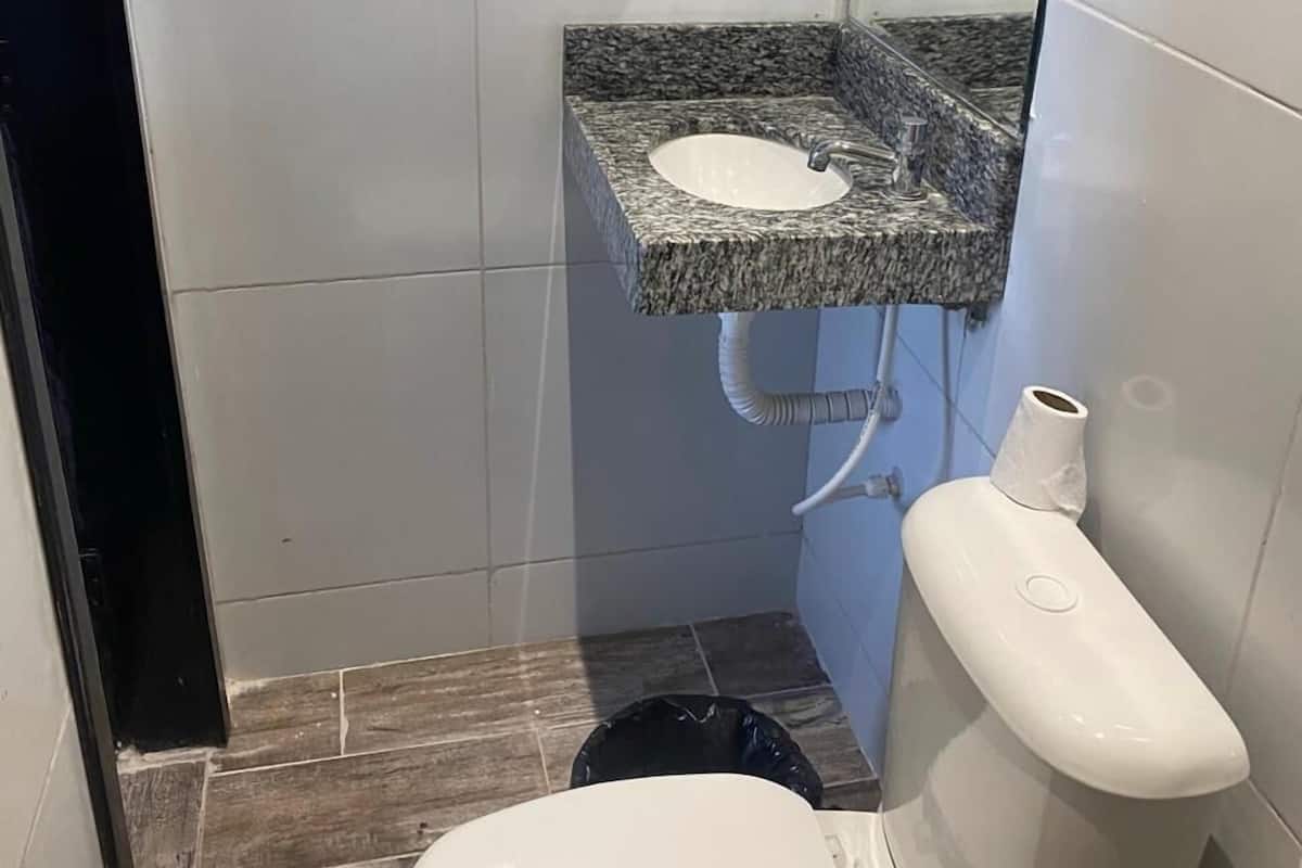 A small, compact bathroom with a white toilet, a granite sink, and a glass shower enclosure.
