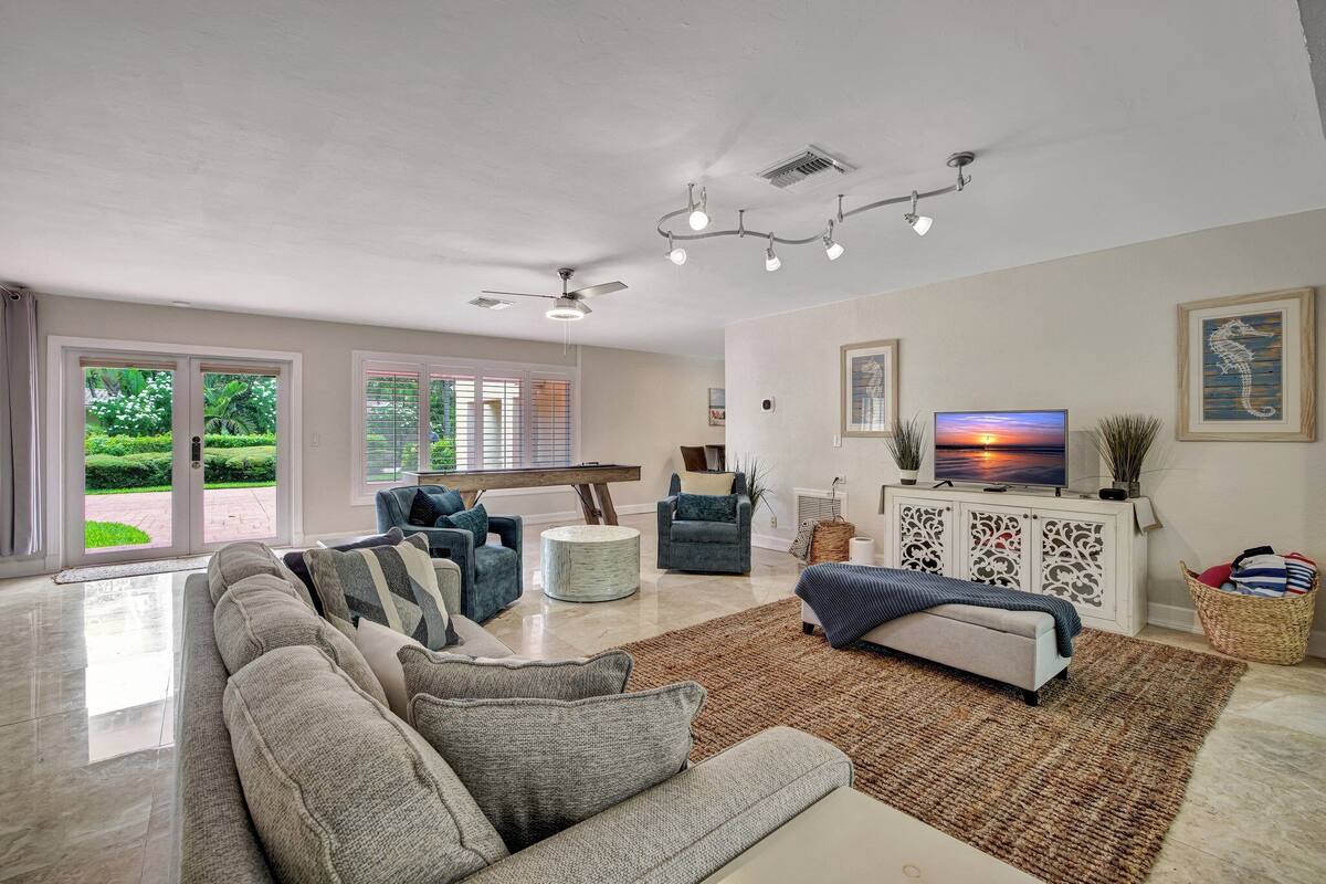 A spacious living room with a large sofa, a television, and a dining area with a wooden table and chairs.