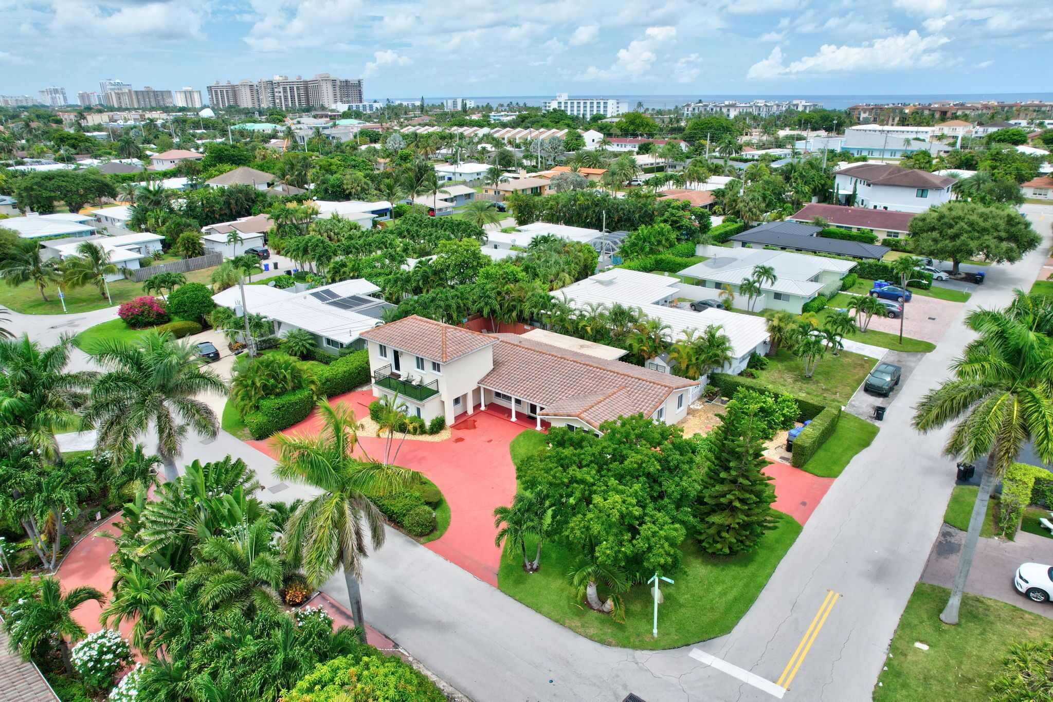 A residential area with houses, palm trees, and a red driveway.