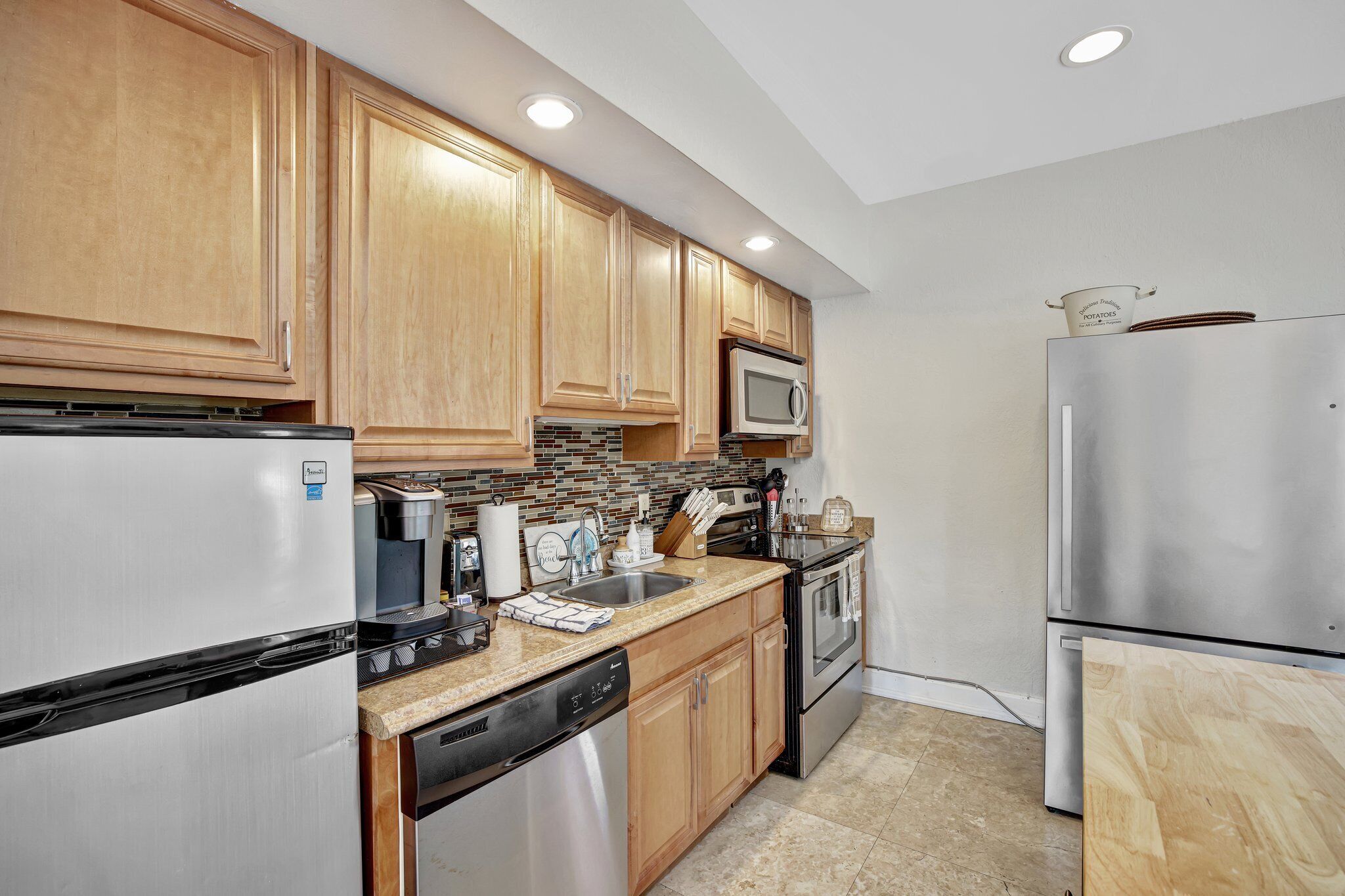 A modern kitchen with wooden cabinets, stainless steel appliances, and a tiled backsplash.