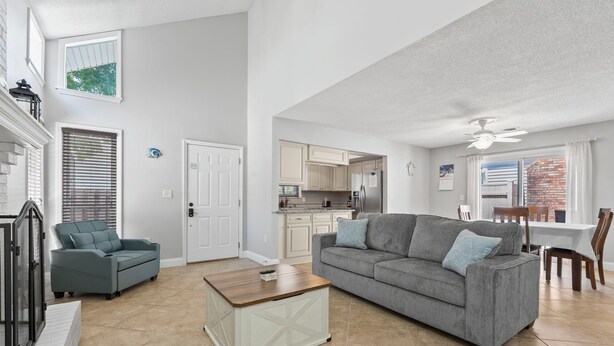 A spacious living room with a grey sofa, a coffee table, and a dining area with a table and chairs. - Charming 3BR Beach House w/ Yard & Grill ☀️ (North Myrtle Beach)