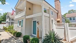 A two-story house with a balcony, a chimney, and a small front yard with plants. - Charming 3BR Beach House w/ Yard & Grill ☀️ (North Myrtle Beach)