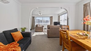 A modern living room with a sofa, a dining table, and a TV.