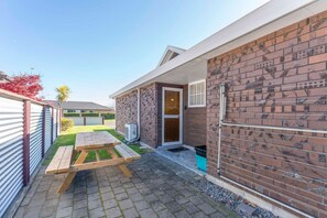 A residential property with a patio, a wooden table, a brick wall, and a door.