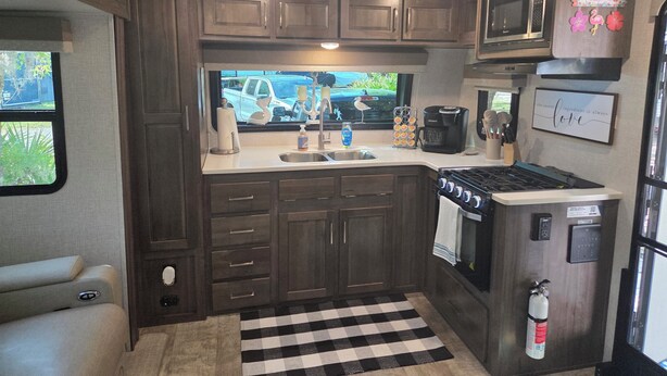A compact RV kitchen with a microwave, stove, sink, and cabinets. - Sunshine Serenity @ Crystal River, Florida (Crystal River)