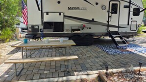 A Microlite Flagstaff RV with a picnic table, a small kitchen area, and an American flag. - Sunshine Serenity @ Crystal River, Florida (Crystal River)