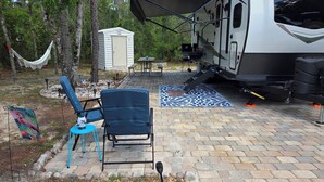 A campsite with a white RV, blue chairs, a hammock, and a small shed. - Sunshine Serenity @ Crystal River, Florida (Crystal River)