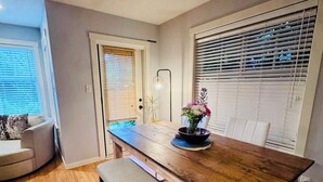 Een eetgedeelte met een houten tafel, een bank en een vaas met bloemen.