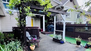 Een achtertuin met een overdekte patio, een kleine tuin en een houten omheining.