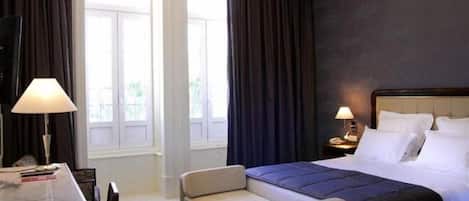 Una habitación de hotel con cama, sofá, escritorio y lámpara de araña.