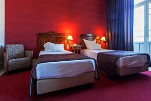 A hotel room with two beds, a red carpet, and a wooden chair. - Curia Palace Hotel & Spa (Tamengos)