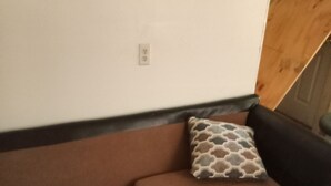 Ein braunes Sofa mit einem gemusterten Kissen vor einer weißen Wand.