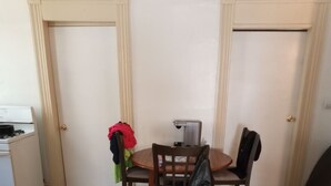 Ein kleiner Essbereich mit einem runden Tisch, zwei Stühlen, einer Kaffeemaschine und einem Herd im Hintergrund.