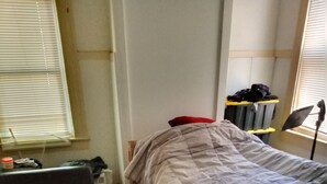 Ein kleiner, kompakter Raum mit einem Einzelbett, einer Schlafcouch und einem kleinen Tisch.