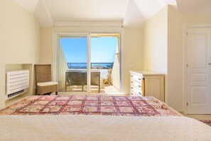 Een slaapkamer met een bed, een dressoir, een stoel en uitzicht op het balkon.
