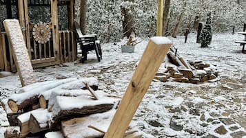 A rustic wooden cabin with a snow-covered exterior, a wooden door, and a bench outside.