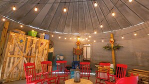 A spacious room with a high, curved ceiling and a central circular table surrounded by red chairs. - Hermann Grain Bins BNB  (Hermann)
