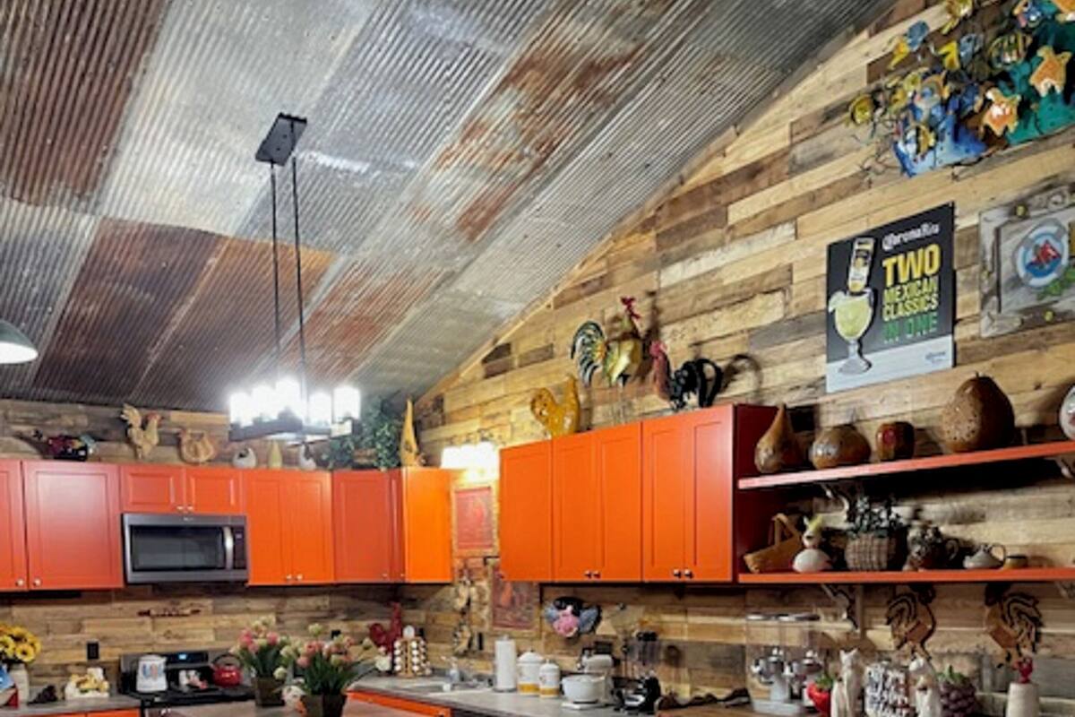 A kitchen with orange cabinets, a microwave, and various decorative items on the walls.