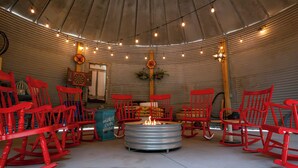 A rustic interior with red rocking chairs arranged around a central fire pit. - Hermann Grain Bins BNB  (Hermann)