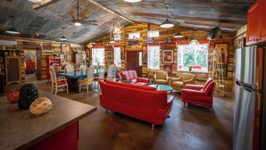 A rustic interior with a dining area, red sofas, and a kitchen with a refrigerator. - Hermann Grain Bins BNB  (Hermann)