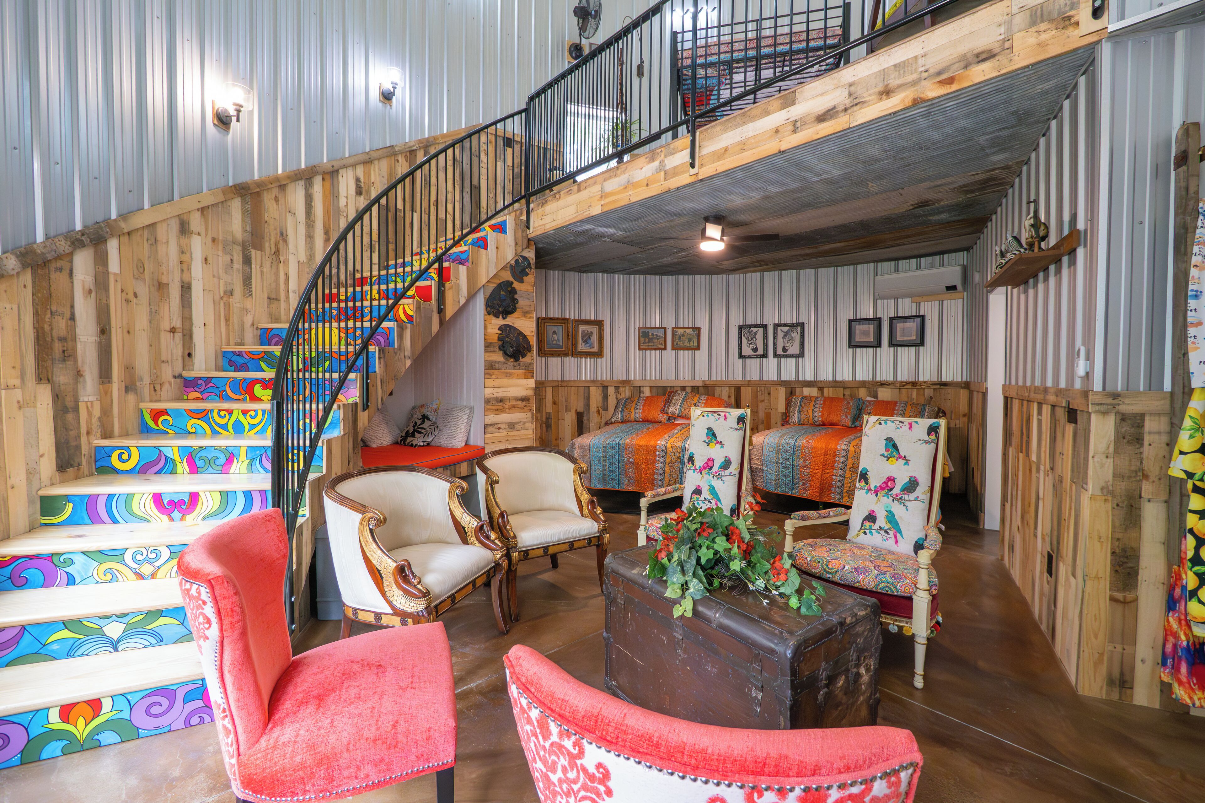 A rustic interior with a wooden staircase, multiple seating areas, and a loft space.