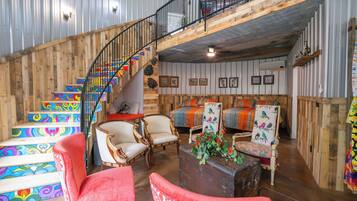 A rustic interior with a wooden staircase, multiple seating areas, and a loft space.