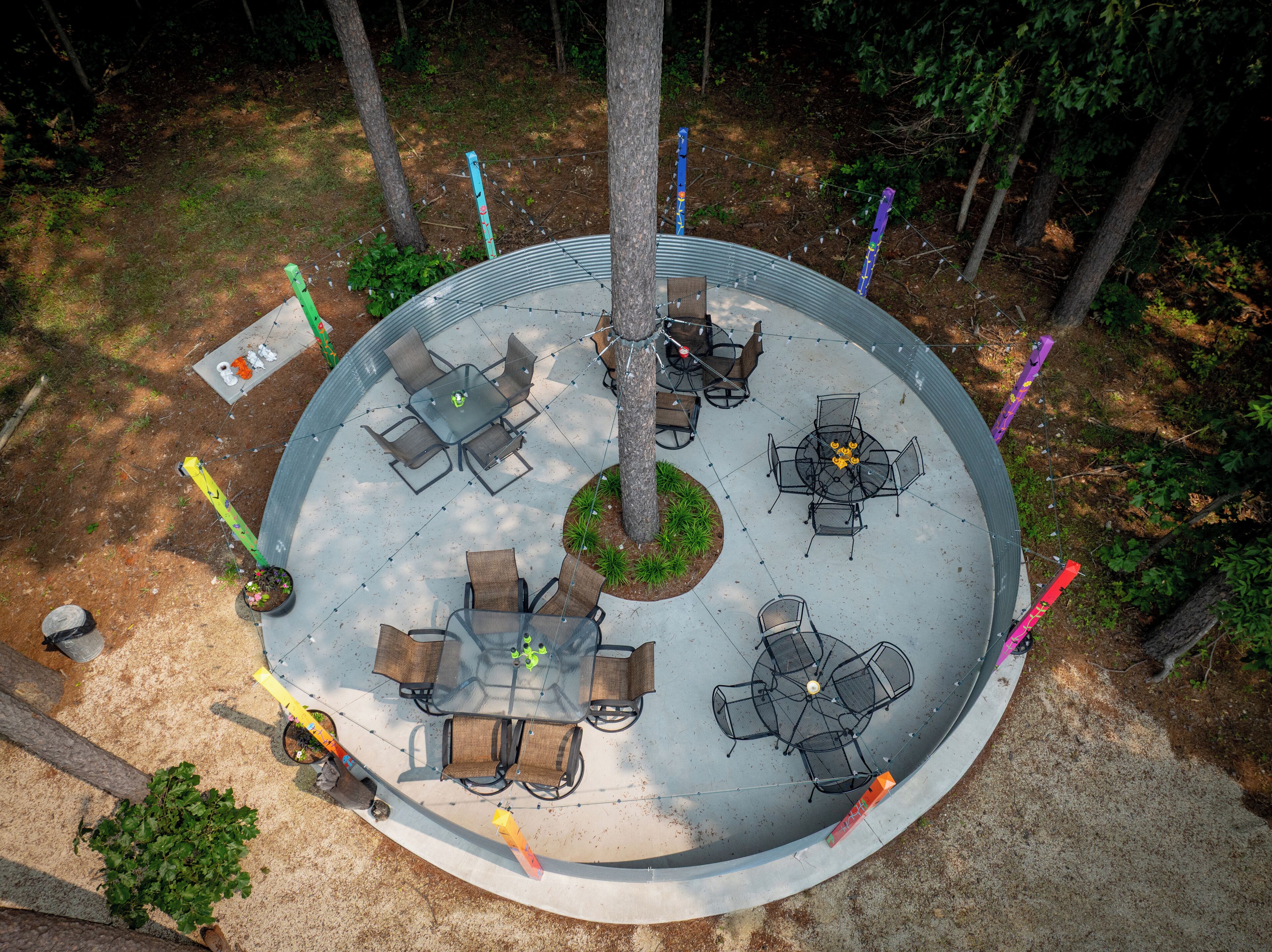 An outdoor patio area with multiple seating arrangements, including round and square tables, surrounded by chairs.