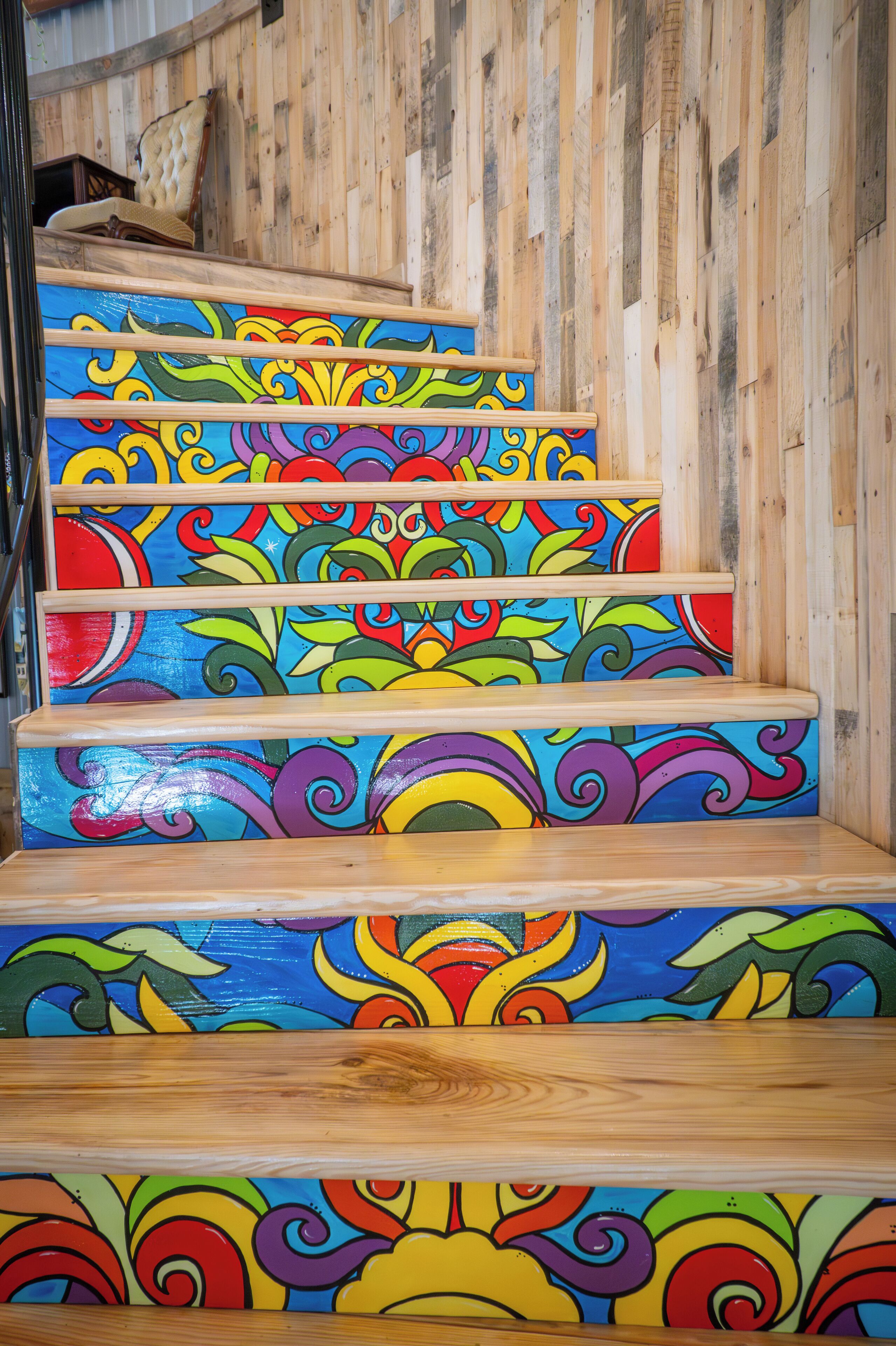 A wooden staircase with colorful, painted steps featuring floral and abstract patterns.