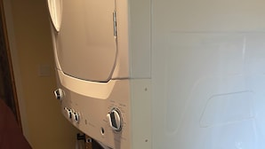 A white washing machine with a control panel, a yellow bottle, and a wooden floor. - A little bit of Heaven! (Grand Forks)