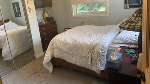 A bedroom with a bed, dresser, mirror, window, and a chandelier. - A little bit of Heaven! (Grand Forks)