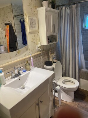 Ein Badezimmer mit weißem Waschbecken, Toilette, Spiegel und Duschvorhang.