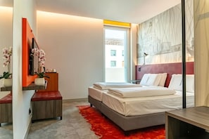 Une chambre à coucher moderne avec un lit, une table de chevet et un tapis rouge.