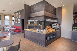 A modern cafe with a central counter, seating area, and a wall with chalkboard menus. - Campanile Venice Mestre (Venice)