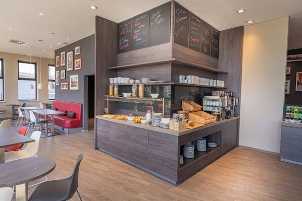 A modern cafe with a central counter, seating area, and a wall with chalkboard menus. - Campanile Venice Mestre (Venice)