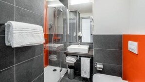 Une salle de bain moderne avec une douche à parois de verre, un lavabo blanc et des toilettes.