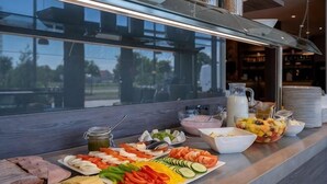 A buffet with various food items and a view of the outdoors through a window. - Campanile Venice Mestre (Venice)