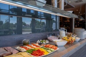 Un buffet proposant une variété de plats, avec une vue sur l’extérieur par une fenêtre.