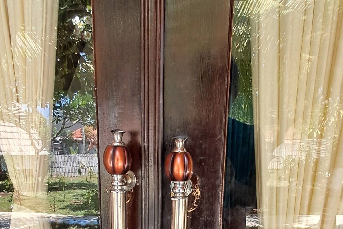 A wooden door with two metallic handles and a keyhole.