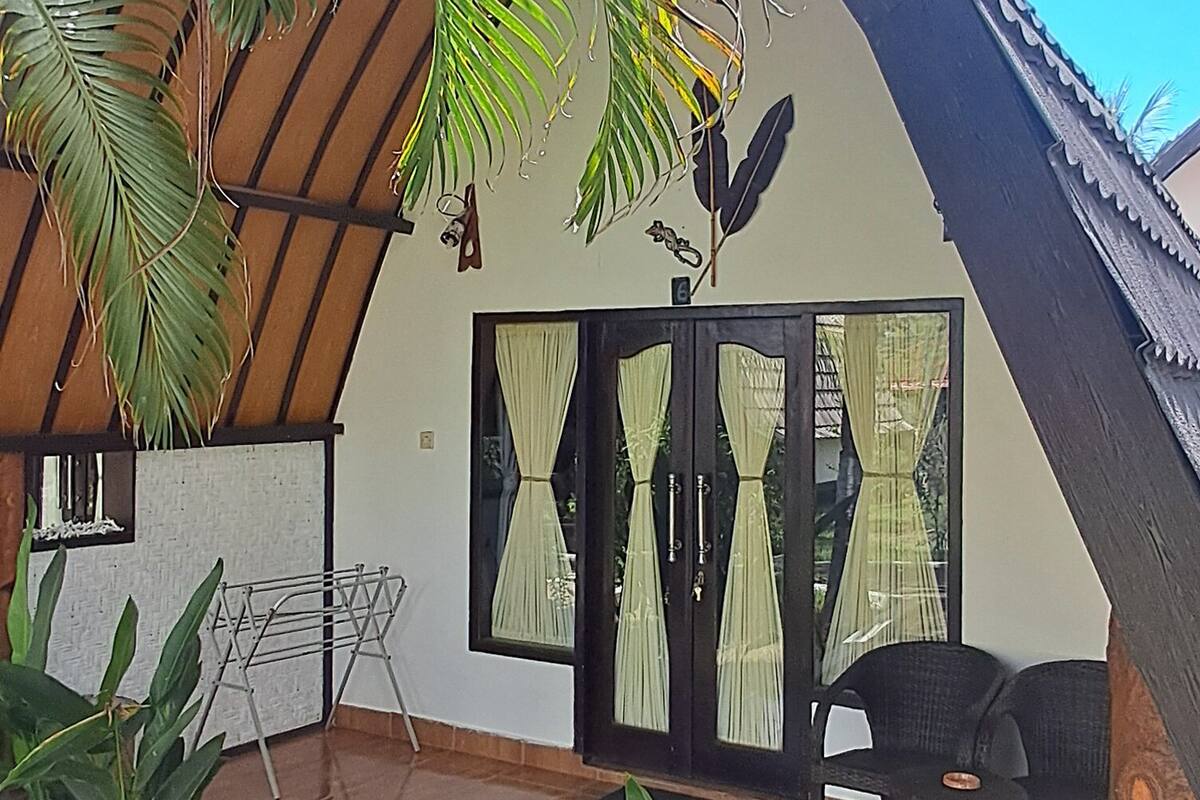 A covered outdoor area with a tiled floor, a seating area with chairs, and a variety of plants.