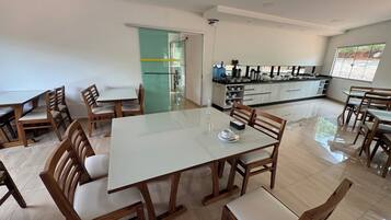 Un comedor amplio con una mesa grande y varias sillas, una cocina con electrodomésticos modernos y vistas al exterior a través de un ventanal.