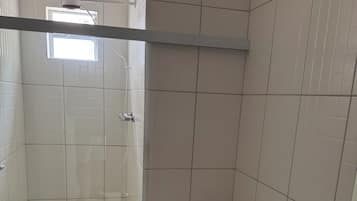 Un baño con cabina de ducha de vidrio, inodoro y lavabo con lavamanos rojo.