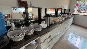 A long buffet counter with baskets, cups, and food items. - Hotel Fazenda Vale dos Guaribas (Abaíra)