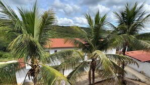 A courtyard with palm trees, a red-roofed building, and a stone-paved area. - Hotel Fazenda Vale dos Guaribas (Abaíra)